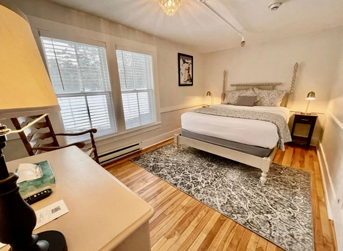Hotel room with white walls two large windows and a white queen bed in North Conway