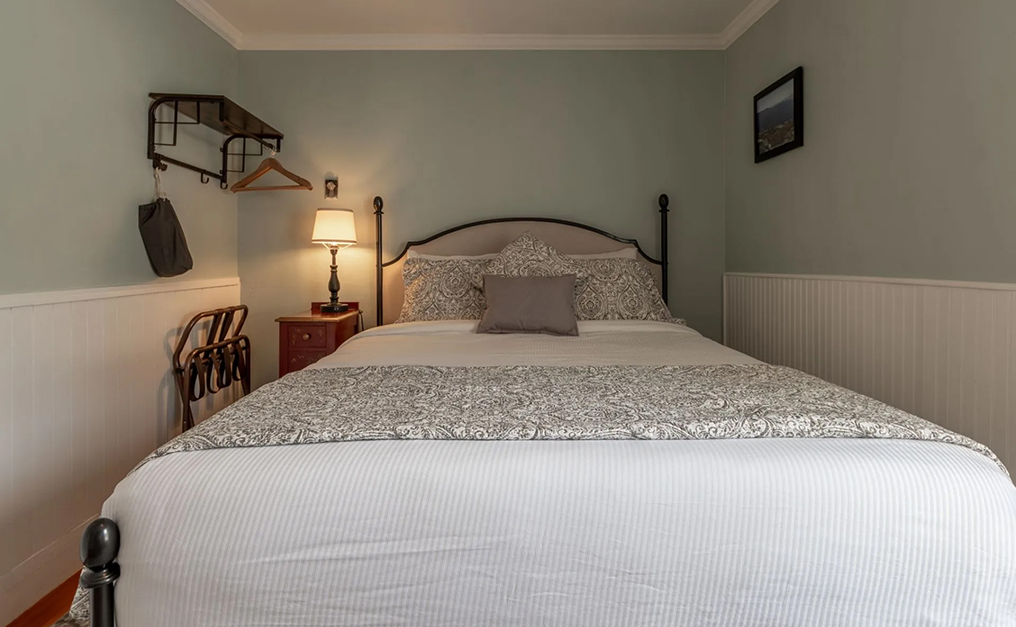 Queen bed with a hanger rack on one side and a nightstand on the other