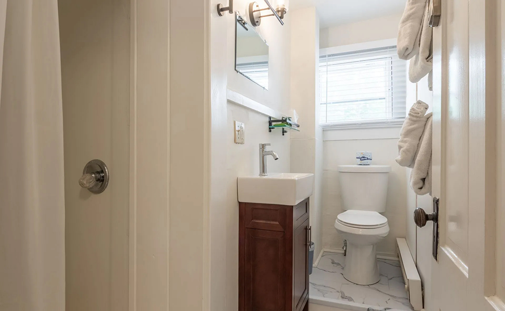 Short hallway with a walk in shower a sink and a toilet
