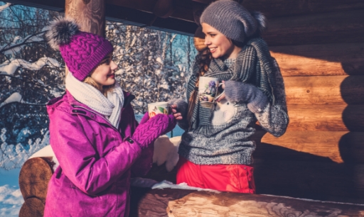 Red flower petals and wine bottle and two wine glasses on bed with white sheets