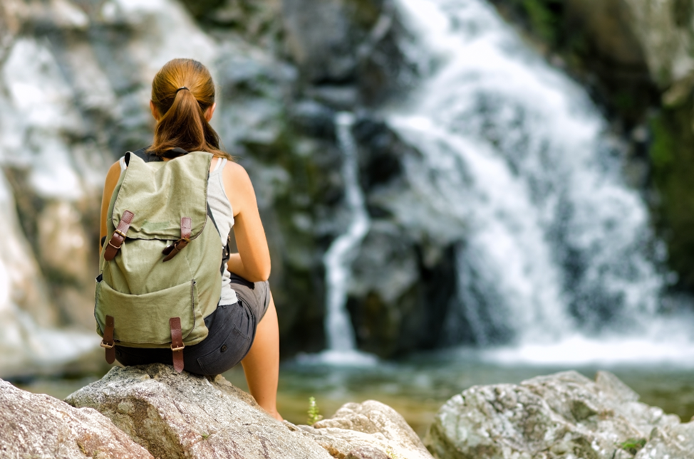 young woman looking at waterfall after hike